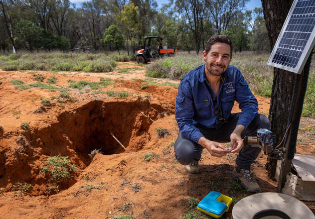 Senior Field Ecologist Andy Howe beside an entry to a Northern Hairy-nosed Wombat burrow on Richard Underwood Nature Refuge, Queensland.